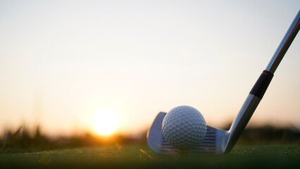 Golf clubs and balls on a green lawn in a beautiful golf course with morning sunshine.