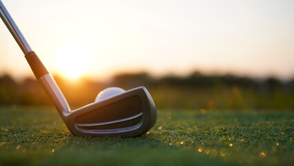 Golf clubs and balls on a green lawn in a beautiful golf course with morning sunshine.