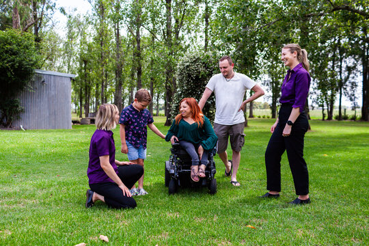 Family on rural property chatting with occupational therapist and speech pathologist outdoors