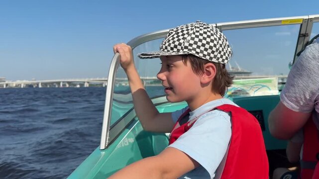boy enjoys riding on motor boat with his father lon Neva river, Saint Petersburg