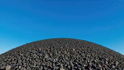 Stack of dark volcanic stones under a clear blue sky