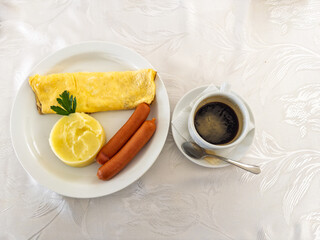 Hearty rolled omelette with creamy mashed potatoes and savory breakfast sausages on a pristine white plate
