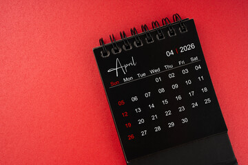 April black desk calendar for 2026 year on red cover background with copy space.