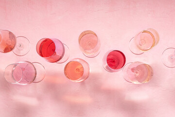 Rose wine assortment, overhead flat lay shot, a variety of hues and tints, on a pink background, many wine glasses