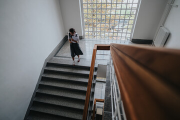 A student descends a staircase in a brightly lit school building. The scene captures a moment of...