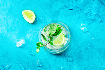 Lime lemonade, or limeade, in a glass with lime, mint, and ice. Mojito mocktail or cocktail, overhead flat lay shot with a place for text