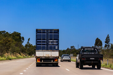 Ute car and truck on highway with blue sky copy space traveling together on divided road