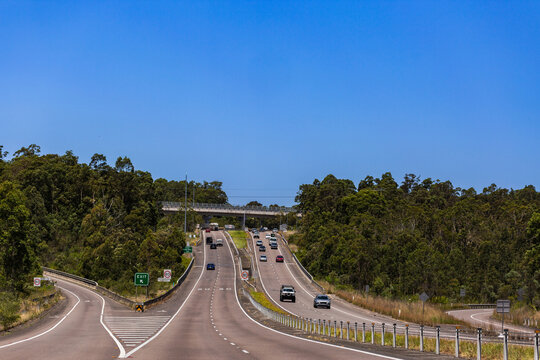 cars travelling on highway with exit sign with speed change to 80km/ph