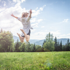 Happy young woman jumping on the meadow in mountains.