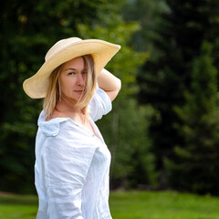 Beautiful young woman in a hat posing in the summer park.