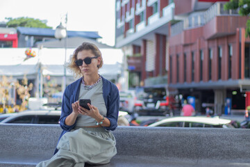 Smiling mature woman in suit with coffee and laptop on balcony. Confident and elegant entrepreneur...