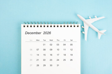 December 2026 calendar and airplane toy on blue color background, Travel plan concepts.