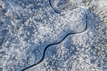 A curvy road snakes through a white snowy expanse seen from above