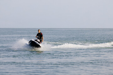 Young man rides a jet ski across turquoise waters during seaside vacation. Concept water sports...