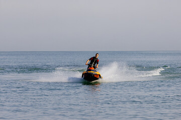 Young man speeds on a jet ski under the bright summer sun. Concept freedom, adrenaline, and water...
