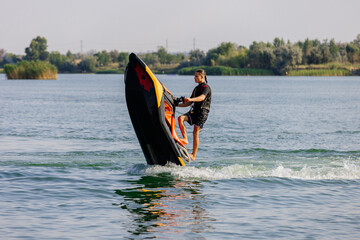 Young man speeds on a jet ski under the bright summer sun. Concept freedom, adrenaline, and water...