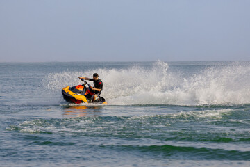 Young man speeds on a jet ski under the bright summer sun. Concept freedom, adrenaline, and water...