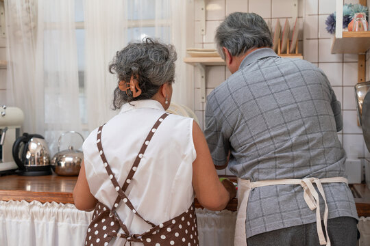Happy elderly Asian couple washing dishes in the sink together in the kitchen at home. Senior retirement in love with healthy - Powered by Adobe