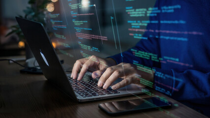 Programmer typing code on a laptop with holographic data overlay