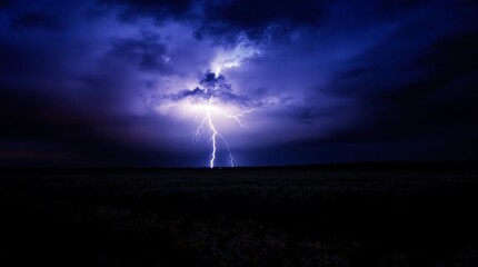 Obraz premium Dramatic Night Thunderstorm with Powerful Lightning Strike Illuminating Dark Clouds Over Rural Landscape