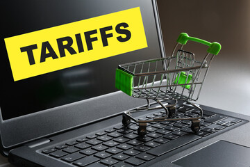 An empty shopping cart on a laptop keyboard and "Tariffs" written on the screen. A concept for new customs tariffs.