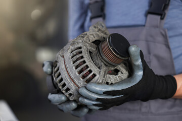 Auto part. Professional mechanic with alternator near indoors, closeup. Space for text
