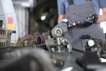 Professional mechanic with camshaft indoors, focus on different auto parts
