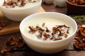 Tasty cream soup with mushrooms and thyme in bowl on wooden table, closeup