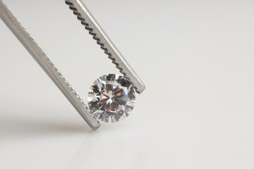 Tweezers with shiny diamond on light background, closeup. Space for text