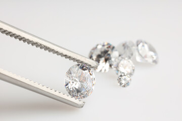 Tweezers with shiny diamonds on light background, closeup