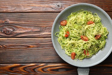 Tasty zucchini noodles with tomatoes and thyme on wooden table, top view. Space for text