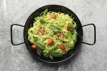 Tasty zucchini noodles with tomatoes, pine nuts and basil on grey table, top view