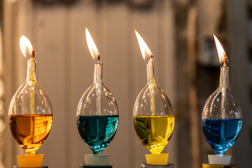 Colorful paraffin oil burning in tear-drop shaped glass vials on a Hanukkah menorah.