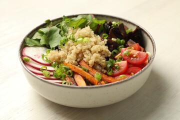 Healthy vegetarian food. Delicious Buddha bowl with quinoa, mushrooms and vegetables on light wooden table, closeup