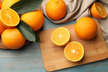 Fresh oranges and leaves on light blue wooden table, flat lay