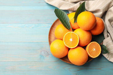 Fresh oranges and leaves on light blue wooden table, top view. Space for text