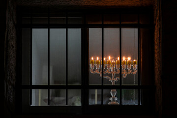Eight Chanukah candles glowing brightly in a Jerusalem, Israel window on the final night of the Festival of Lights, an eight-day Jewish holiday.