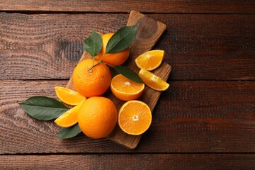 Fresh ripe oranges and leaves on wooden table, top view. Space for text