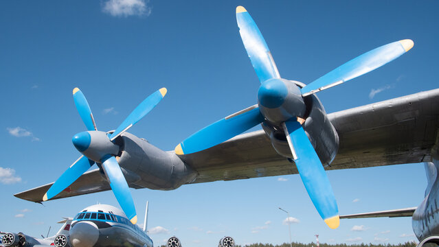 An iconic Soviet aircraft stands proudly, featuring striking blue propellers beneath a bright sky, reflecting the rich heritage of Russian aviation technology.