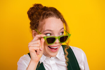 Young Woman with Green Glasses on Yellow Background Showing Excitement and Joyful Expression in...