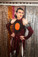 Drag Queen Poses Glamorously in Front of Shimmering Sequin Curtains at a Vibrant Queer Event