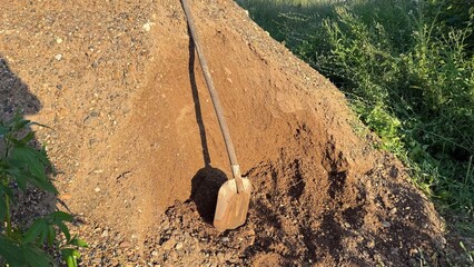 A large pile of sand, gravel, and a shovel for mixing concrete and building paving stones or...