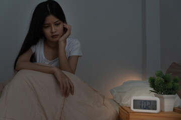 asian woman in bed late trying to sleep suffering insomnia, sleepless or scared in a nightmare, looking sad worried and stressed. Tired and headache or migraine waking up in the middle of the night.