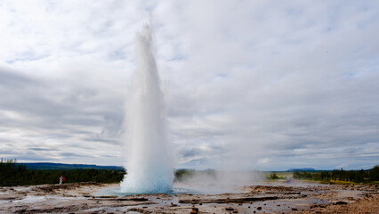 Strokkur Geyser erupts spectacularly against the scenic backdrop of Icelands beautiful landscapes