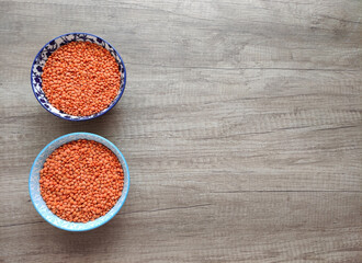 Dried small red lentils in a decorative plate on a wooden background