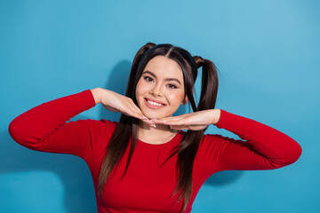 Attractive brunette girl in a trendy red top posing confidently with a charming smile against a...