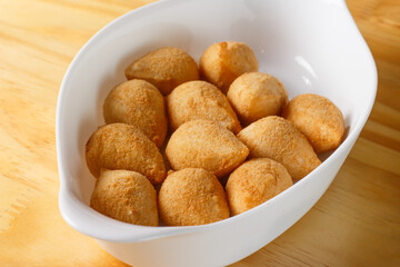 Typical Brazilian snack. Coxinha in a white bowl on a wooden table.
