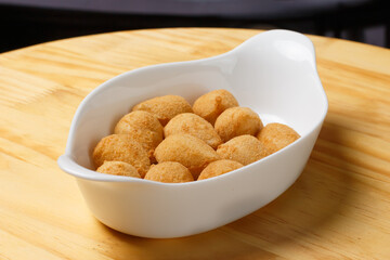 Typical Brazilian snack. Coxinha in a white bowl on a wooden table.