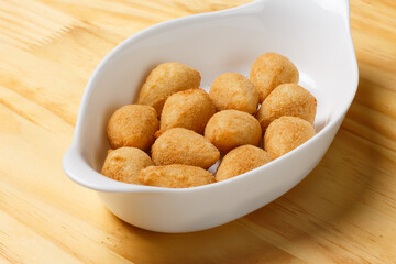 Typical Brazilian snack. Coxinha in a white bowl on a wooden table.