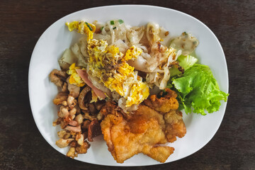 Stir fried rice noodles with roasted and fried chicken served with fresh lettuce and chili sauce. Close up stir fried fresh rice fat noodles with chicken and egg. Asian food style. Delicious Thai food